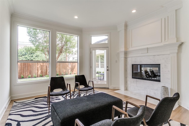 living room featuring a fireplace, ornamental molding, and light wood-type flooring