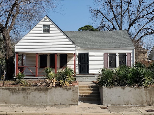 bungalow with a porch and roof with shingles