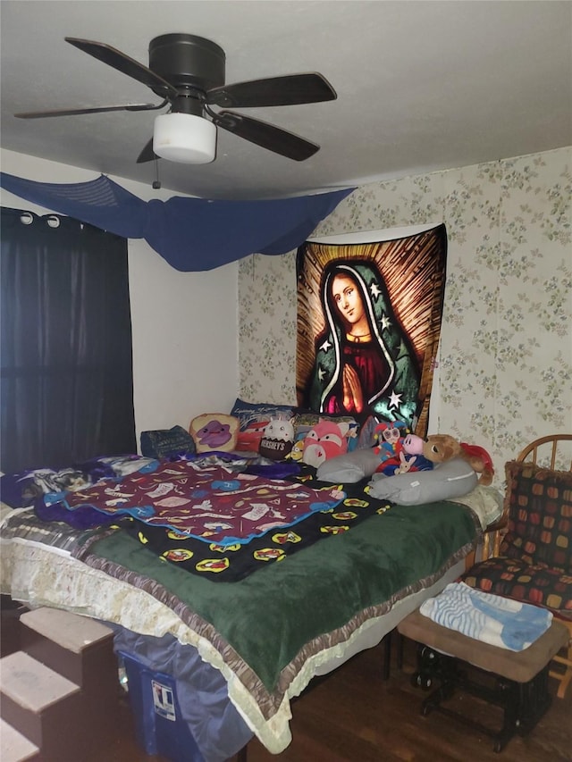 bedroom with a ceiling fan, wood finished floors, and wallpapered walls