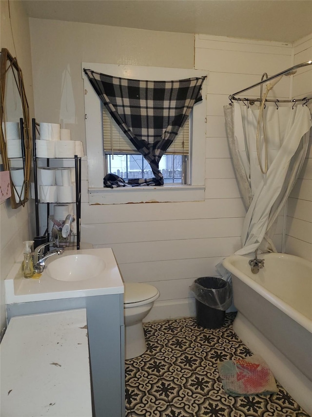 bathroom featuring tile patterned flooring, toilet, wood walls, vanity, and shower / tub combo with curtain