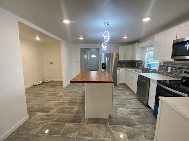 kitchen with sink, wooden counters, appliances with stainless steel finishes, white cabinetry, and a kitchen island