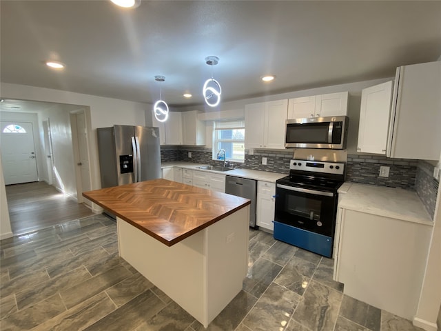 kitchen with sink, wooden counters, stainless steel appliances, a center island, and white cabinets