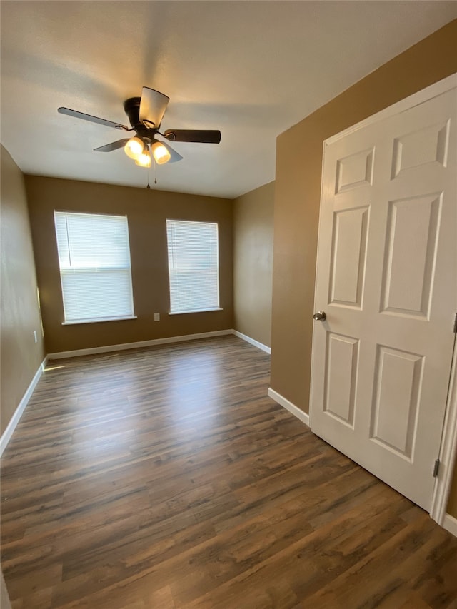 empty room with ceiling fan and dark hardwood / wood-style flooring