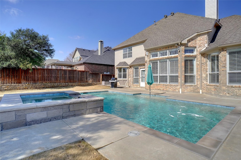 view of swimming pool with a grill and an in ground hot tub