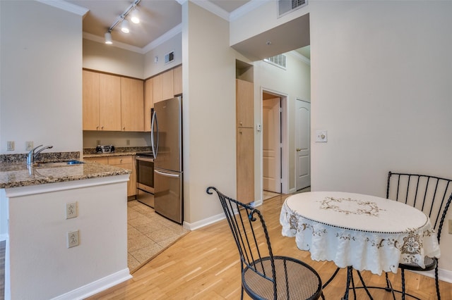 kitchen featuring sink, crown molding, dark stone countertops, light brown cabinets, and stainless steel appliances