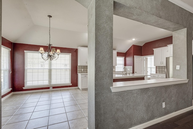 kitchen featuring a wealth of natural light, lofted ceiling, white cabinets, and light tile patterned floors