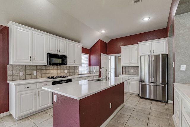 kitchen featuring light countertops, lofted ceiling, light tile patterned floors, black appliances, and a sink