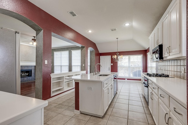 kitchen featuring visible vents, black appliances, a sink, arched walkways, and light tile patterned floors