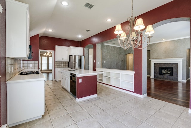 kitchen featuring pendant lighting, an island with sink, a chandelier, light tile patterned floors, and black appliances