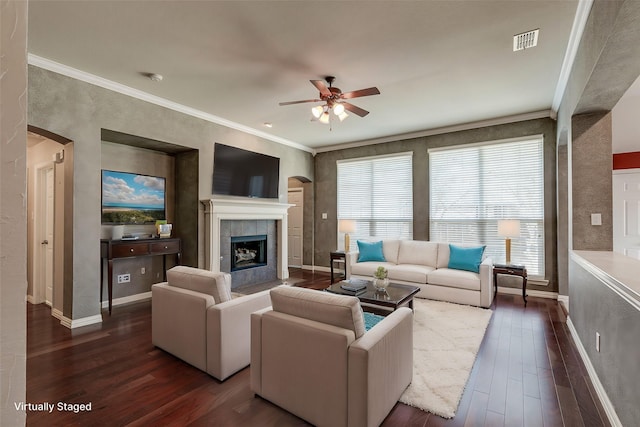 living area featuring arched walkways, visible vents, crown molding, and dark wood-type flooring