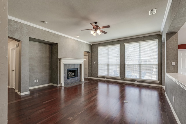 unfurnished living room featuring visible vents, a tiled fireplace, ornamental molding, wood finished floors, and arched walkways