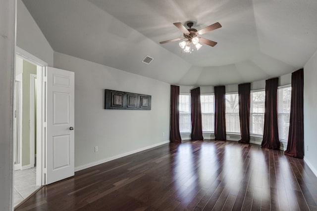 spare room featuring visible vents, lofted ceiling, wood finished floors, baseboards, and ceiling fan