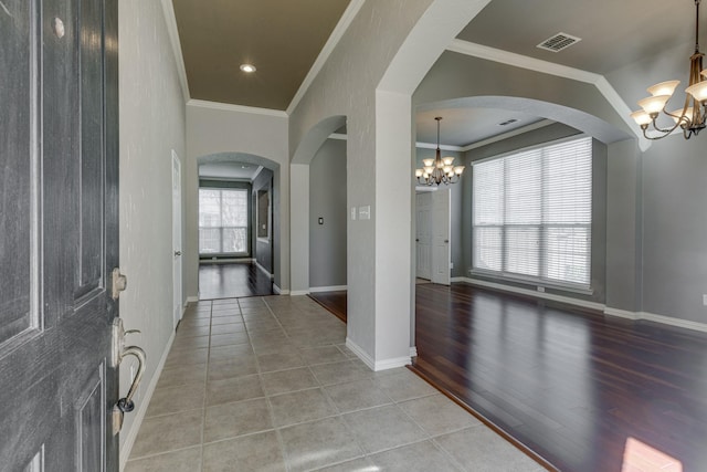 foyer featuring visible vents, baseboards, ornamental molding, light tile patterned floors, and an inviting chandelier