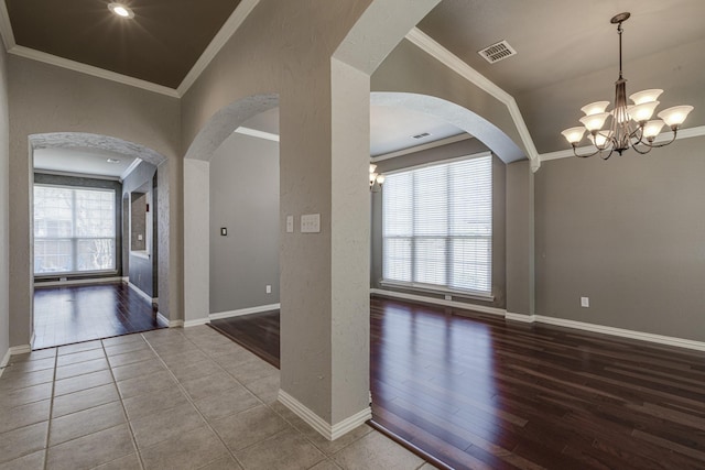 empty room featuring a wealth of natural light, visible vents, and crown molding