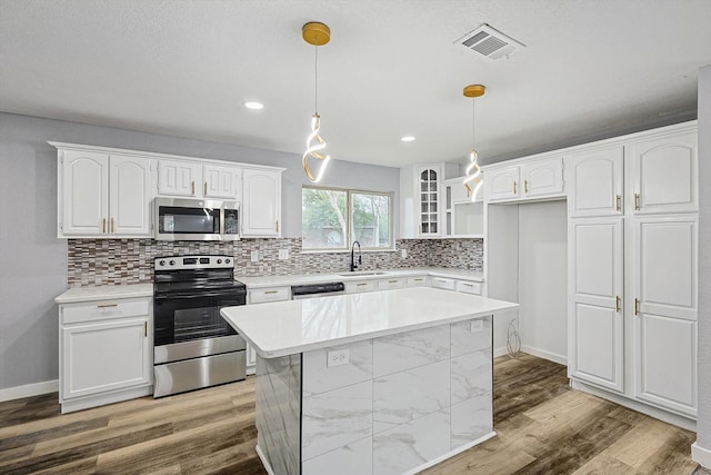 kitchen featuring sink, white cabinetry, a center island, hanging light fixtures, and stainless steel appliances