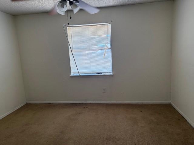 carpeted empty room with ceiling fan and a textured ceiling