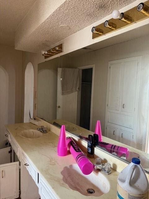 bathroom featuring a bathing tub, vanity, and a textured ceiling