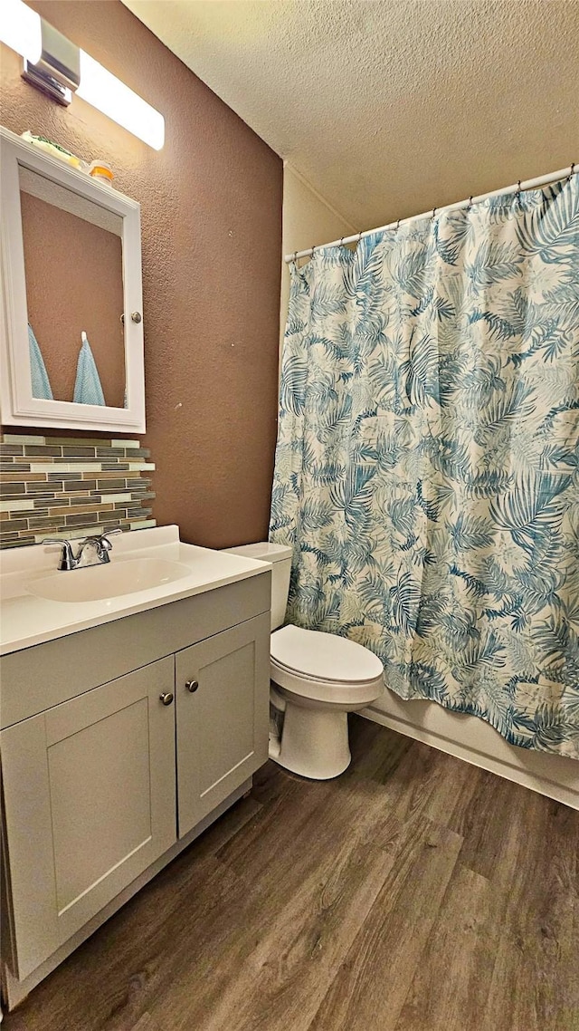 bathroom featuring hardwood / wood-style flooring, tasteful backsplash, vanity, a textured ceiling, and toilet