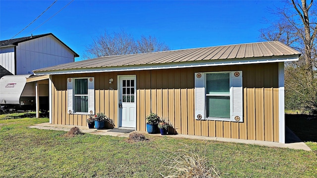 view of front facade featuring metal roof, board and batten siding, and a front yard