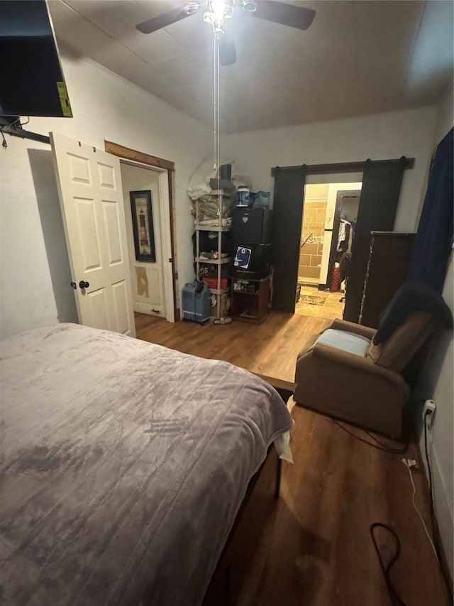 bedroom featuring connected bathroom, wood-type flooring, and ceiling fan