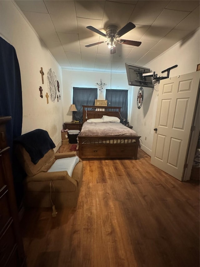 bedroom featuring hardwood / wood-style floors, ornamental molding, and ceiling fan