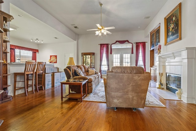 living room with hardwood / wood-style flooring, ceiling fan, a fireplace, and french doors