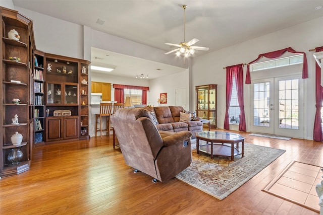 living room featuring french doors, ceiling fan, and light hardwood / wood-style flooring