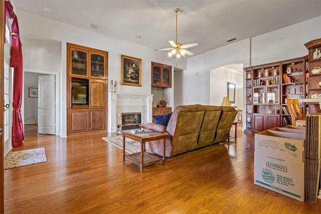 living room featuring ceiling fan, a fireplace, and wood-type flooring