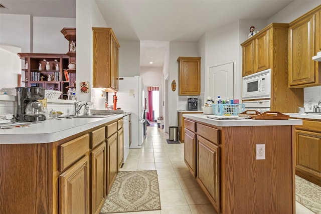 kitchen featuring light tile patterned flooring, sink, backsplash, a center island, and white appliances