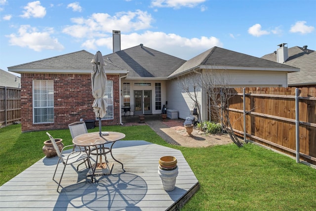 back of property featuring a wooden deck and a lawn