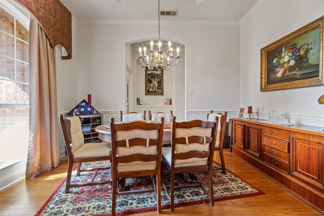 dining room featuring crown molding, an inviting chandelier, and light hardwood / wood-style floors