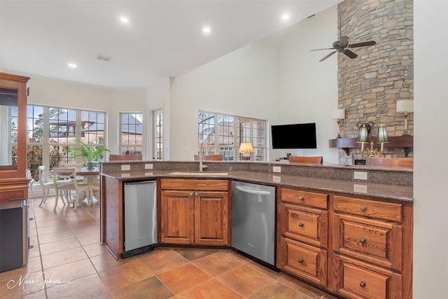 kitchen with sink, crown molding, dishwasher, a high ceiling, and dark stone counters