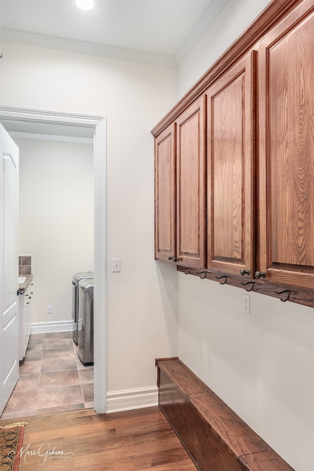 clothes washing area with crown molding, wood-type flooring, and washing machine and clothes dryer