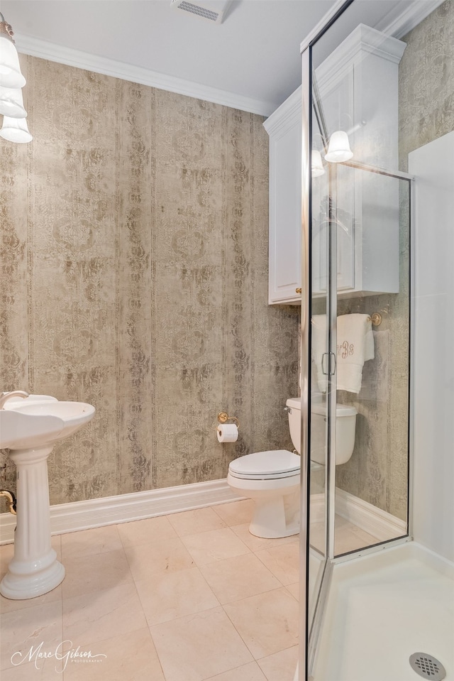 bathroom featuring a shower with door, crown molding, tile patterned floors, and toilet