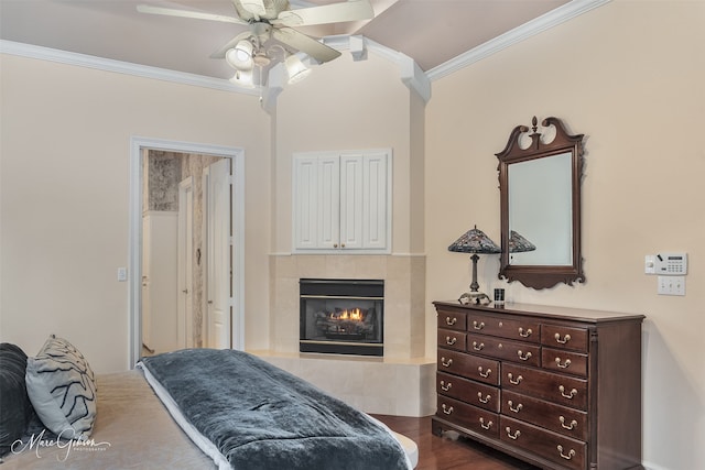 bedroom featuring crown molding, dark wood-type flooring, ceiling fan, and a fireplace