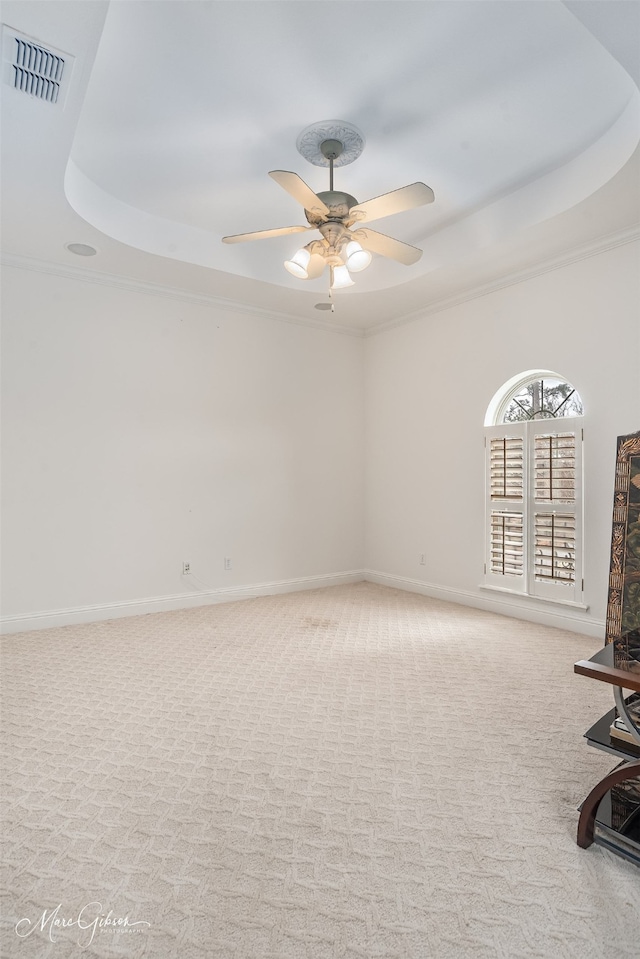 carpeted spare room with ornamental molding, ceiling fan, and a tray ceiling