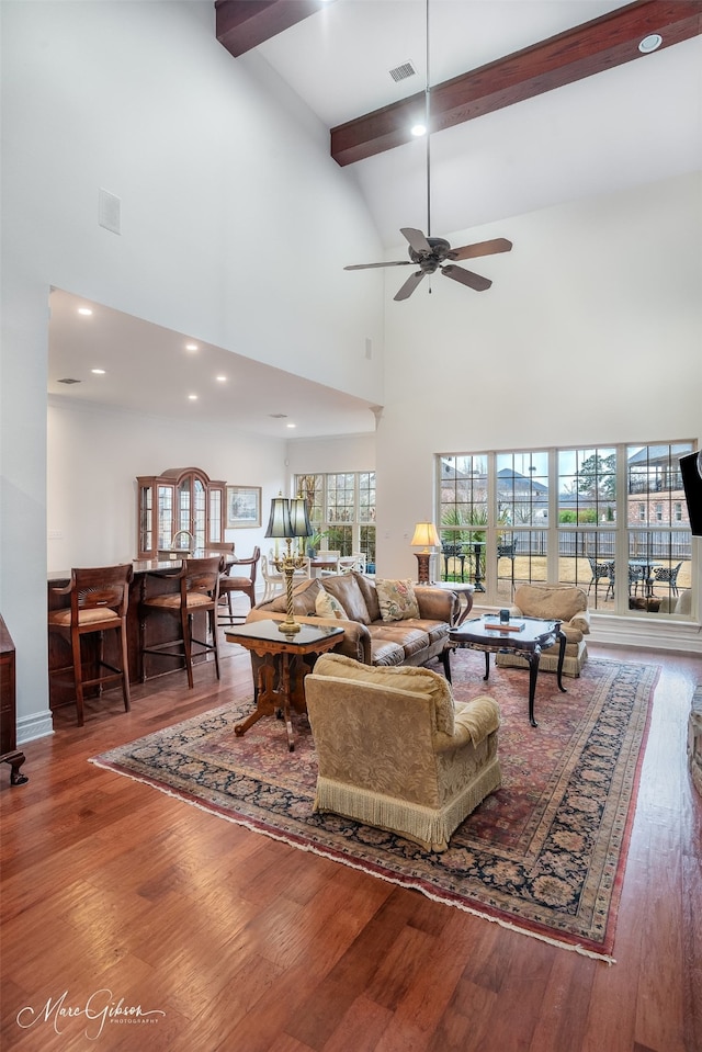 living room featuring ceiling fan, wood-type flooring, high vaulted ceiling, and beamed ceiling