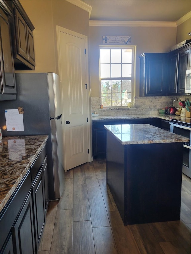 kitchen featuring crown molding, a kitchen island, stainless steel appliances, hardwood / wood-style floors, and decorative backsplash