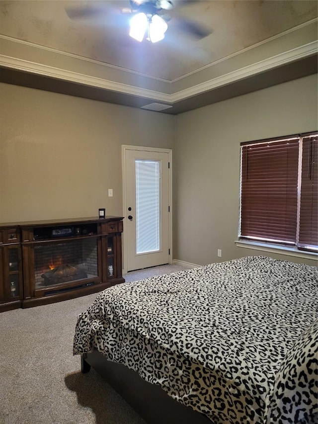 carpeted bedroom with ceiling fan, ornamental molding, and a raised ceiling