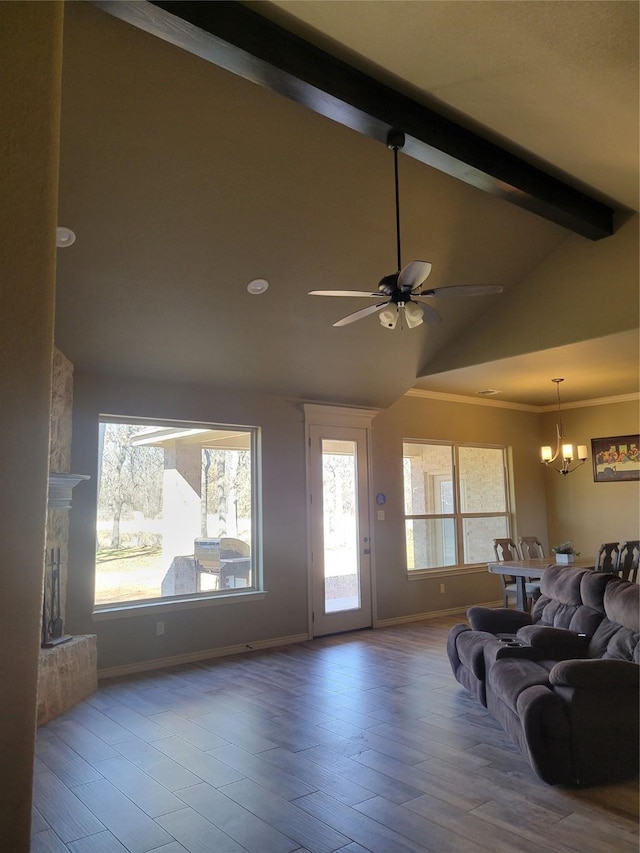 living room featuring crown molding, ceiling fan with notable chandelier, hardwood / wood-style flooring, lofted ceiling with beams, and a stone fireplace