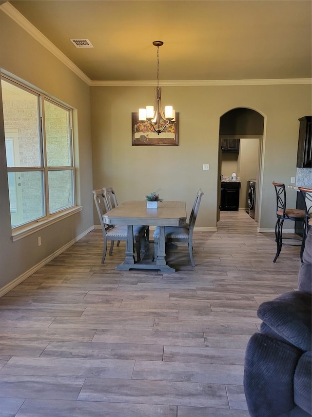 dining area featuring a notable chandelier, crown molding, and light hardwood / wood-style floors