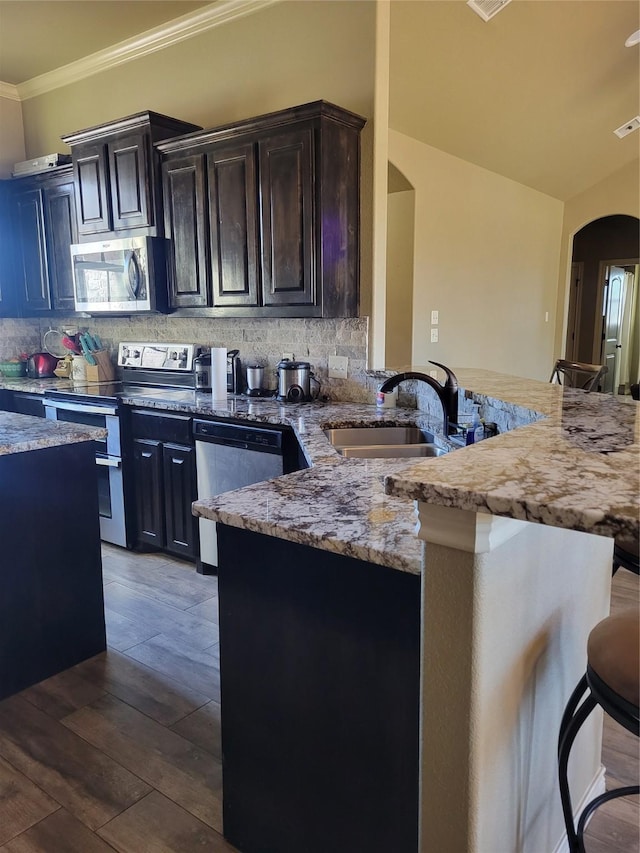 kitchen with a breakfast bar, sink, backsplash, kitchen peninsula, and stainless steel appliances