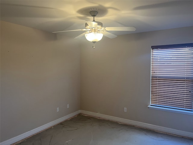 spare room with a ceiling fan and baseboards