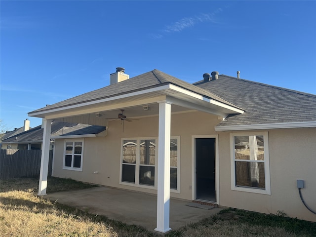 rear view of property featuring roof with shingles, a patio, a chimney, stucco siding, and ceiling fan