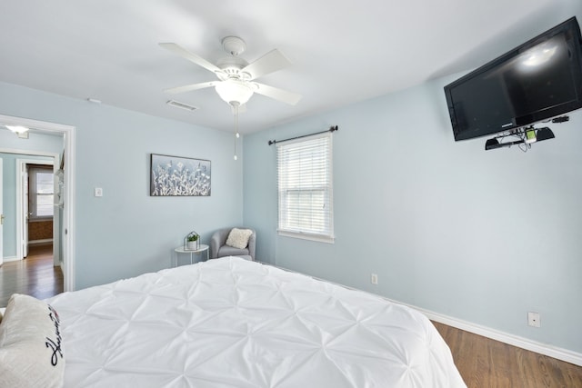 bedroom featuring multiple windows, dark wood-type flooring, and ceiling fan