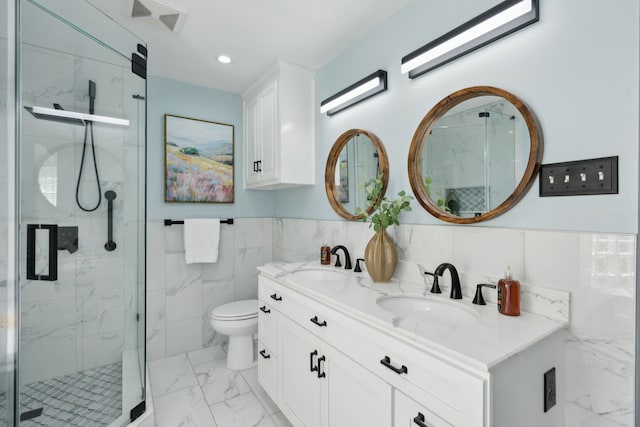 bathroom with vanity, toilet, a shower with shower door, and tile walls