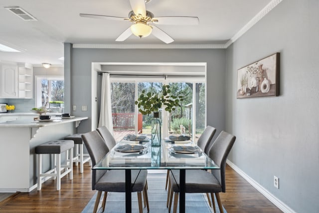 dining area with dark hardwood / wood-style flooring, crown molding, and plenty of natural light