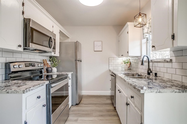 kitchen with pendant lighting, sink, stainless steel appliances, light hardwood / wood-style floors, and white cabinets