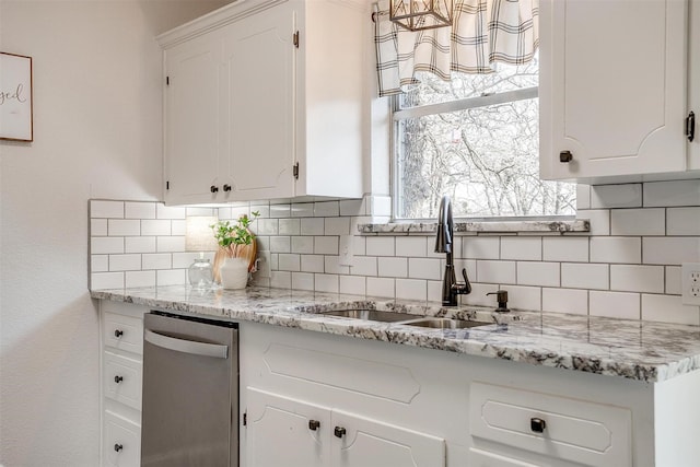 kitchen with tasteful backsplash, dishwasher, sink, white cabinets, and light stone countertops