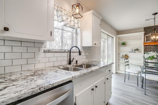 kitchen with hanging light fixtures, dishwasher, sink, and white cabinets